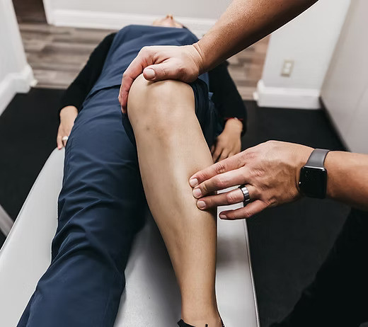 un professionnel qui palpe le tibia de son patient allongé